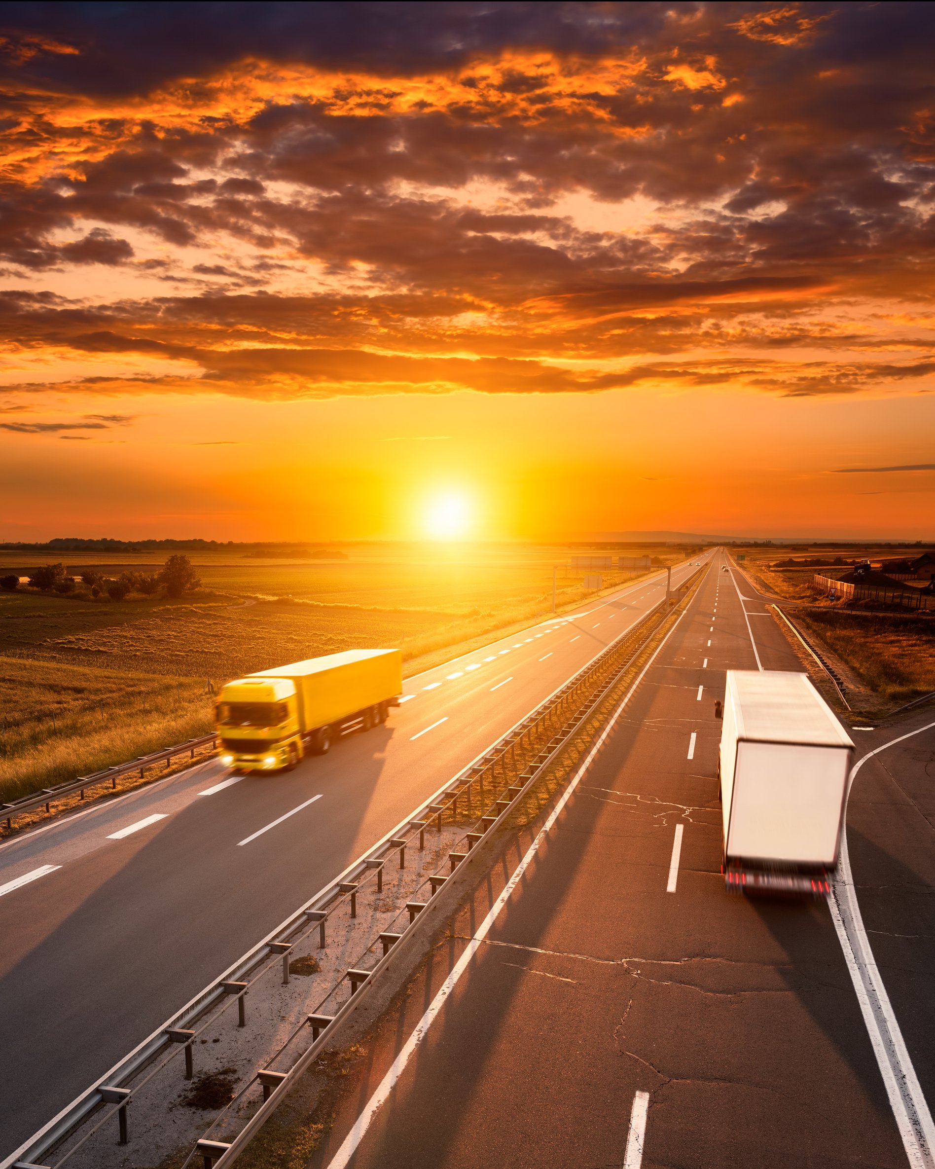 Two trucks on the highway at sunset